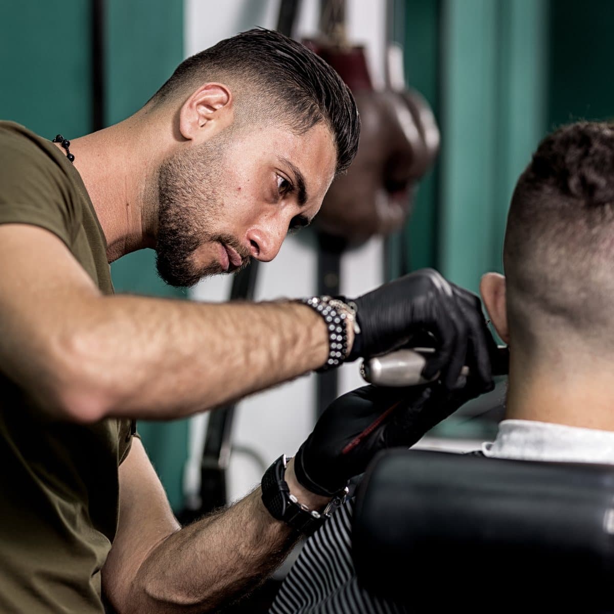 A barber finishing a fade for a client in the chair.