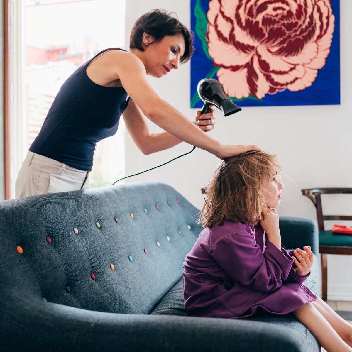 A mobile practitioner styling a client’s hair in their own home.