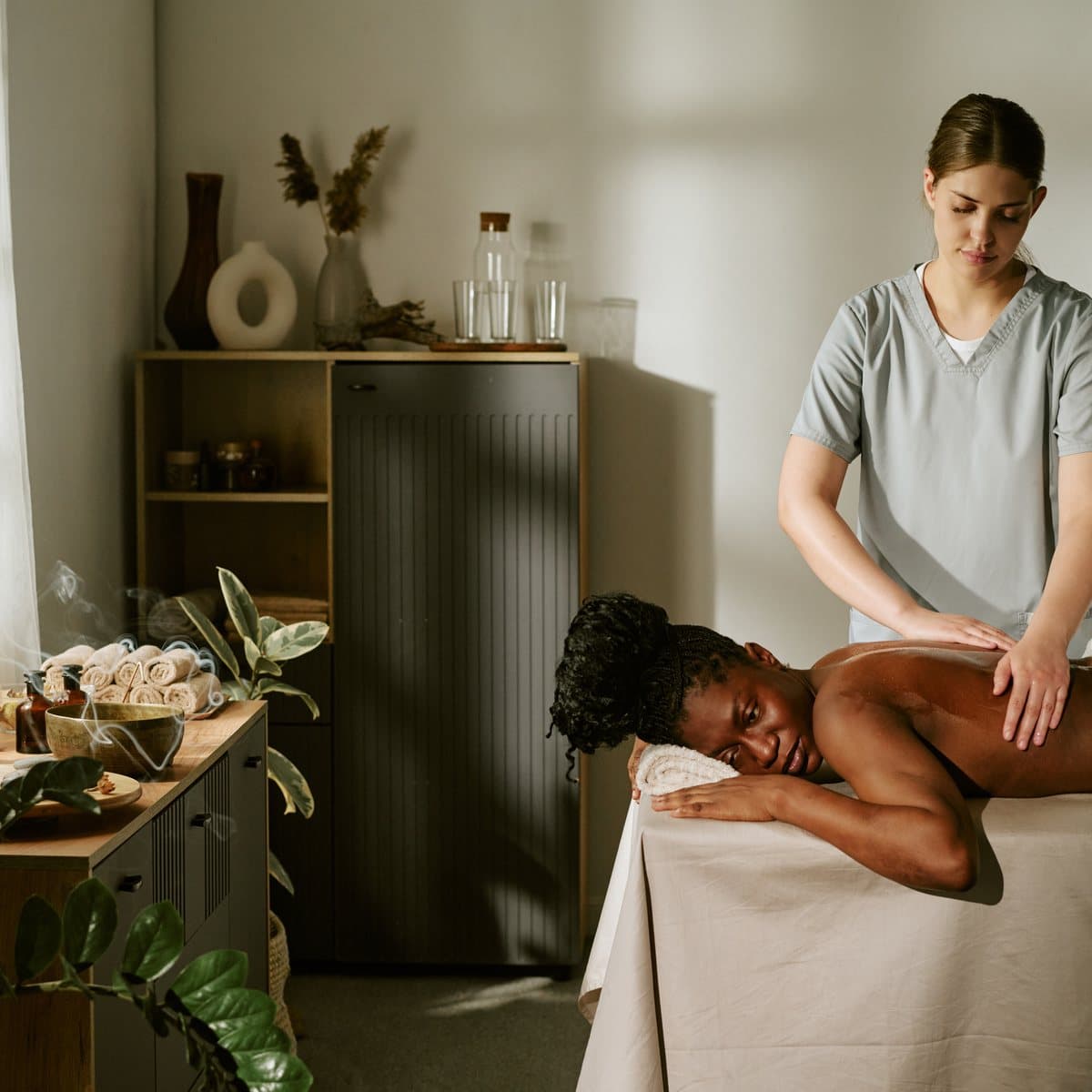 A massage therapist working on a client lying on a massage table.