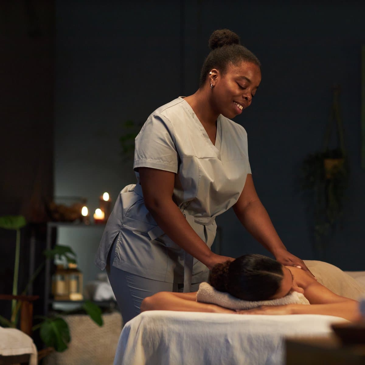 A therapist mid-treatment in a low-lit spa treatment room.
